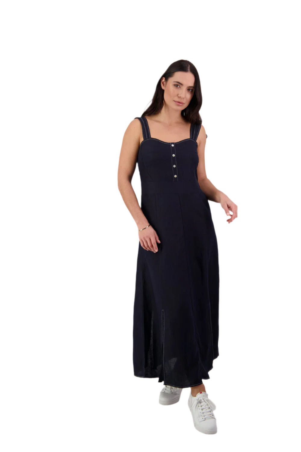 A woman standing wearing a sleeveless navy dress with wide straps, button-up chest buttons, and a slim fit.
